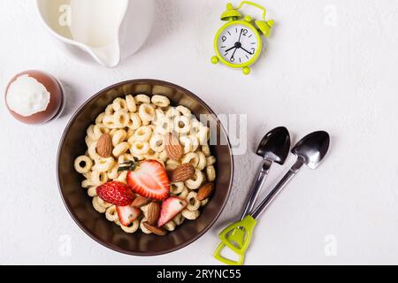 Colazione tradizionale bilanciata. Anelli di grano intero cheerios, frutti di bosco e uovo su tavolo bianco Foto Stock