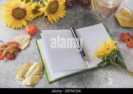 Buongiorno. Concetto di elenco attività. Un bouquet di grandi girasoli, una tazza di caffè e un taccuino vuoto su un tavolo di pietra. Foto Stock