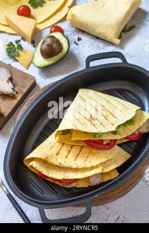 Sandwich di tortillas di mais messicane con avocado, rucola e formaggio su un piano in pietra grigia. Foto Stock