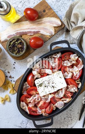 Ingrediente per la feta al forno o la pasta TikTok. Feta al forno a base di pomodori, formaggio feta, aglio ed erbe aromatiche. La via principale Foto Stock