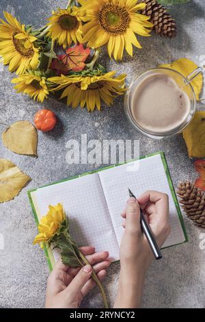 Buon giorno. Concetto di elenco attività. Un bouquet di grandi girasoli, una tazza di caffè e un quaderno vuoto su un tavolo di pietra. Vista dall'alto piatta l Foto Stock