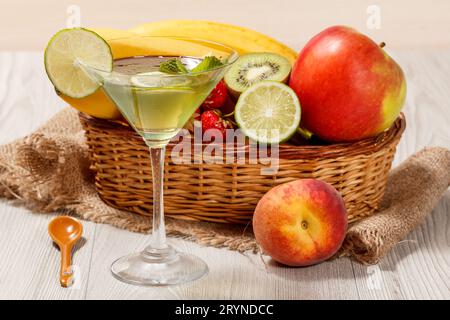 Gelatina Kiwi con pezzi di lime nel bicchiere e frutta fresca nel cestino di vimini Foto Stock