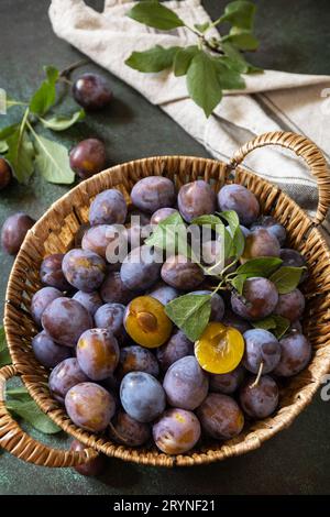 Frutta di fondo, frutta biologica. Cibo ancora vita. Cesto di prugne fresche blu su un tavolo di pietra. Foto Stock
