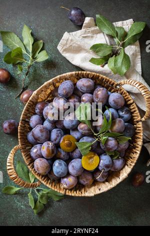 Frutta di fondo, frutta biologica. Cibo ancora vita. Cesto di prugne fresche blu su un tavolo di pietra. Vista dall'alto. Foto Stock