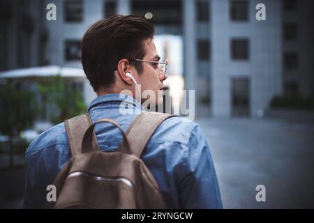 Ritratto di un giovane allegro bell'uomo ben vestito con le cuffie pensando a un nuovo progetto. Foto Stock