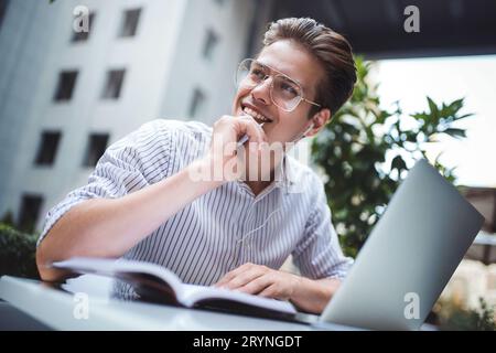 Atteggiamento intelligente. Un bell'uomo che usa un computer portatile e si siede nel bar mentre navighi su internet. Giovane blogger o journa Foto Stock