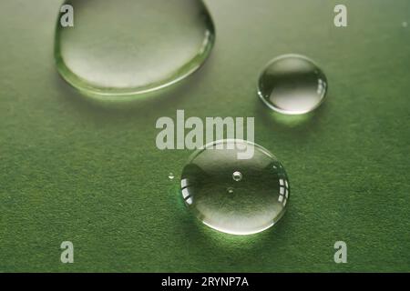 Tre gocce di liquido su sfondo verde. Foto Stock