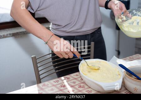 le mani della donna preparano il tiramisù. Tipico dessert italiano Foto Stock