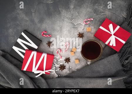 Composizione natalizia con tazza di caffè, caramelle, zucchero e regali sul grigio. Disposizione piatta Foto Stock