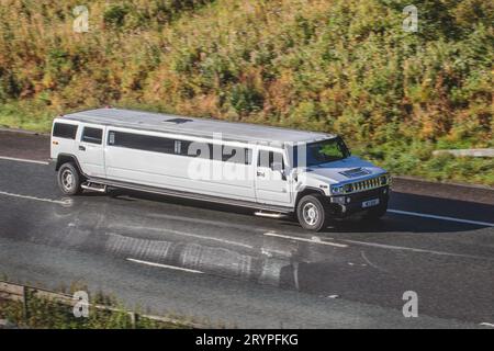 2005 GMC H2 benzina 6000 cc limousine allungata bianca che viaggia a velocità sostenuta sull'autostrada M6 a Greater Manchester, Regno Unito Foto Stock