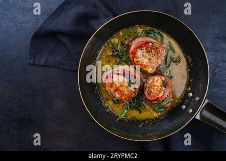 Tradizionali medaglioni di filetto di vitello arrosto con rivestimento di pancetta e foglie di salvia in salsa di burro serviti come vista dall'alto su un battuto rustico Foto Stock