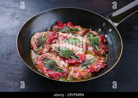 Saltimbocca alla romana di maiale fritto tradizionale italiano con prosciutto di Parma e foglie di salvia serviti da vicino in una classica padella Foto Stock