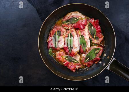 Tradizionale saltimbocca alla romana di maiale fritto italiano con prosciutto di Parma e foglie di salvia servita come vista dall'alto in una classica padella Foto Stock