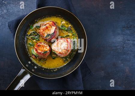 Tradizionali medaglioni di filetto di vitello arrosto con rivestimento di pancetta e foglie di salvia in salsa di burro serviti come vista dall'alto su un battuto rustico Foto Stock
