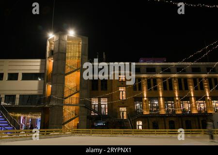 Facciata di un edificio in mattoni con scale esterne in ferro con luci e luci. Edificio industriale convertito in uffici e spazi per la vendita al dettaglio. E dentro Foto Stock