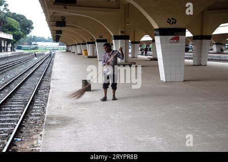 Dhaka, Dhaka, Bangladesh. 2 ottobre 2023. Un addetto alle pulizie spazza il pavimento alla stazione ferroviaria di Kamalapur a Dacca, Bangladesh. I loro instancabili sforzi spesso passano inosservati, eppure svolgono un ruolo vitale nel mantenere la pulizia e l'ordine della stazione. La stazione ferroviaria di Kamalapur è il più grande e vivace snodo ferroviario della nazione. Nota per la sua fusione architettonica di elementi moderni e tradizionali, questa stazione iconica è stata progettata dall'architetto americano Robert Boughey e inaugurata nel 1969. Gestendo quotidianamente un notevole volume di passeggeri e merci, Kamalapur svolge un ruolo fondamentale a Bangla Foto Stock