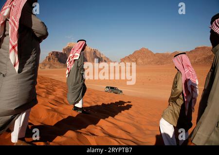 La gente araba e una jeep su una rossa duna di sabbia nel Wadi Rum, Giordania. Foto Stock