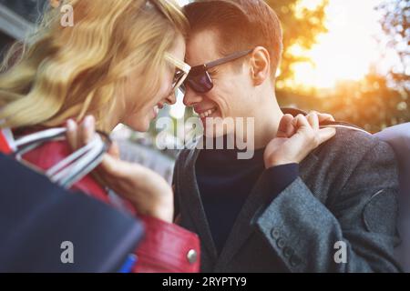 Giovane e bella coppia amorevole il trasporto delle borse della spesa e godendo insieme. Immagine che mostra la coppia giovane di shopping in citta'. Foto Stock