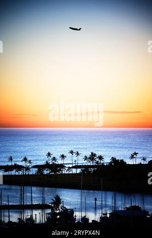 Vista sopraelevata del tramonto sull'Ala Moana Beach Park con un jet passeggeri che decolla sullo sfondo, Honolulu, Hawaii. Foto Stock