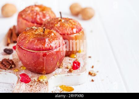 Mele rosse al forno con cannella, noci e miele su sfondo bianco. Dessert autunnale o invernale Foto Stock