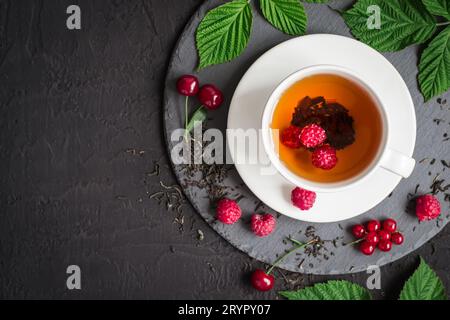 Tè appena fatto e frutti di bosco maturi su sfondo nero Foto Stock