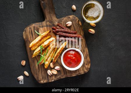 Bicchiere di birra con una varietà di antipasti serviti sul tagliere Foto Stock