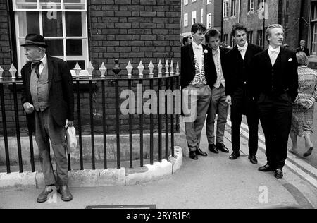 Eton, Windsor, Berkshire, Inghilterra 29 maggio 1990. La regina Elisabetta II visita l'Eton College nel 550° anniversario della scuola. Sesta forma i ragazzi della scuola Eton nella loro uniforme scolastica tradizionale. Lo studente con il gilet colorato è un membro di Pop. (Pop, meglio conosciuto come la società Eton e riservato ai prefetti d'élite.) Il gentiluomo a sinistra, forse un genitore un po' basso, impoverito dalle tasse scolastiche. Foto Stock