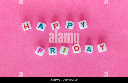 Frasi Happy Friday con perline quadrate su sfondo rosa brillante, vista dall'alto Foto Stock