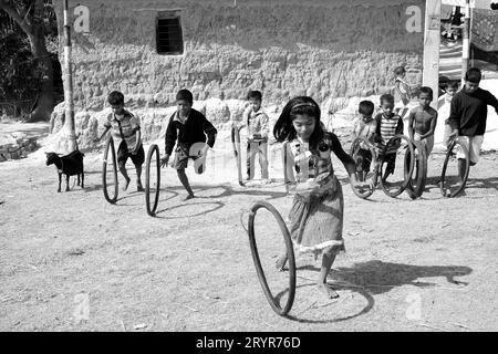 I bambini del villaggio rurale giocano con le gomme ciclistiche al mattino in vacanza a West Bengal, India. Foto Stock