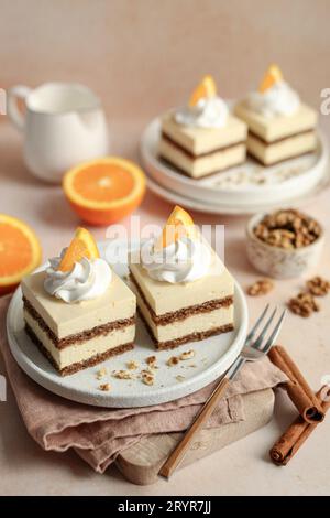 Torta all'arancia e alle noci, decorata con panna montata e fette di arancia fresca, su un piatto bianco. Sfondo arancione. Foto Stock