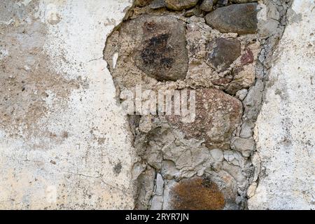 Sfondo di un antico muro di pietra con l'intonaco caduto Foto Stock