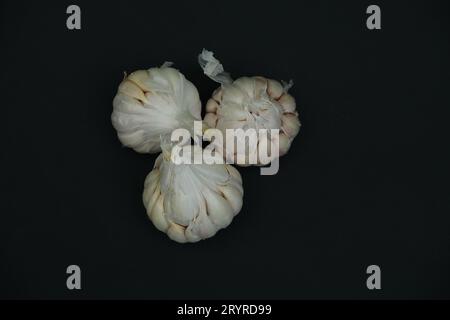 Tre teste di aglio in primo piano su sfondo nero Foto Stock