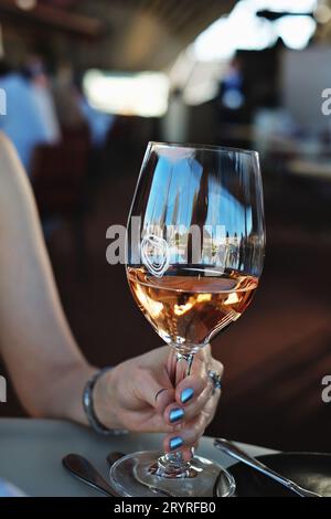 Un riflesso di Sydney, Circular Quay in un bicchiere di vino rosato, tenuto da una donna in una mano al Bennelong Restaurant, Sydney Opera House, Foto Stock