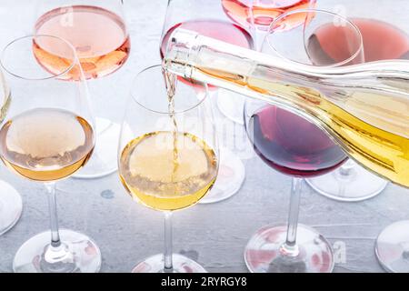Vino bianco versare in un bicchiere durante una degustazione. Vino rosa, rosso e bianco, bevande Foto Stock