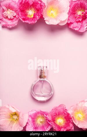 Bottiglia di profumo da donna e fiori di malva rosa su sfondo rosa Foto Stock