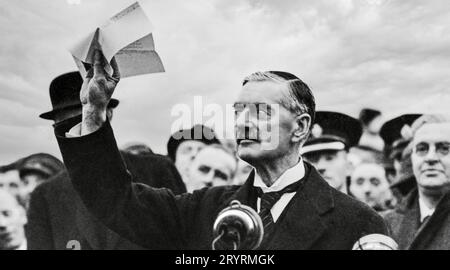 NEVILLE CHAMBERLAIN (1869-1940) il primo ministro britannico torna all'aeroporto di Heston da Monaco il 30 settembre 1938 salutando l'accordo firmato da Hitler e da lui stesso. Sua moglie Anne e' proprio dietro di lui, a destra. Foto Stock