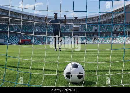 il giocatore di calcio calcia la palla nel gol dello stadio Foto Stock