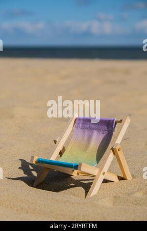 Vacanze soleggiate sulla spiaggia e accessori da spiaggia. Lettino prendisole sul mare. Sedie a sdraio in legno. Concetto di vacanza estiva. Foto Stock