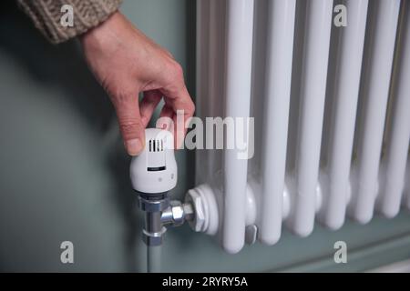 Primo piano della rotazione manuale del termostato sul radiatore a casa per risparmiare energia e denaro Foto Stock