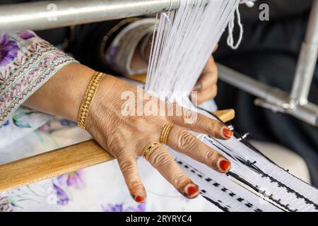 Mani di una vecchia signora degli Emirati che usa una tradizionale macchina per tessere Foto Stock