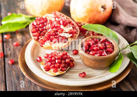 Frutta fresca di melograno succosa in una ciotola di legno su un tavolo rustico. Dieta e cibo sano. Foto Stock