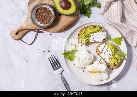 Colazione di Pasqua o brunch. Colazione o spuntino deliziosi - uova in camicia e formaggio spalmabile, pane di segale integrale, avocado Foto Stock