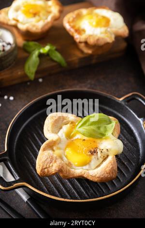 Uova strapazzate in pasta sfoglia con formaggio e pancetta su un piatto di pietra. Idea di colazione, spuntini. Foto Stock