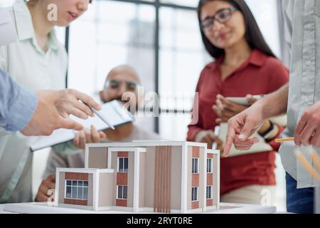 Un gruppo di creativi alla scrivania parla di maquette e parla di progettazione domestica. Foto Stock