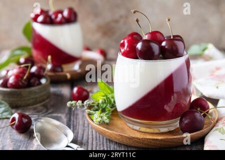 Panna cotta con gelatina di ciliegia dolce su un tavolo rustico. Dessert italiano, cucina fatta in casa. Spazio di copia. Foto Stock