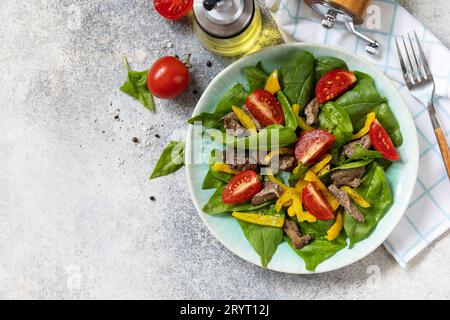 Insalata calda di spinaci giovani, fegato di pollo, pomodori e peperoni grigliati con spezie e aceto balsamico. Dieta keto sana a basso contenuto di carboidrati. V Foto Stock