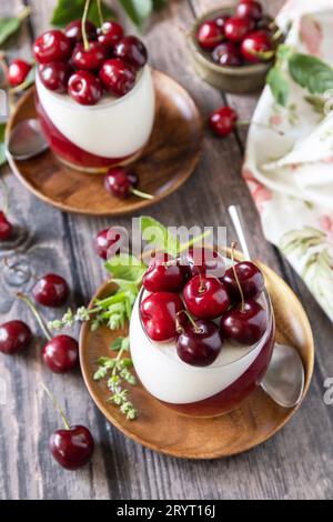 Panna cotta con gelatina di ciliegia dolce su un tavolo rustico. Dessert italiano, cucina fatta in casa. Foto Stock