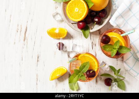 Drink estivo fresco. Bevanda rinfrescante ghiacciata, limonata di cola alla ciliegia all'arancia o cocktail di mojito in bicchiere su un tavolo di legno. Vista da Foto Stock
