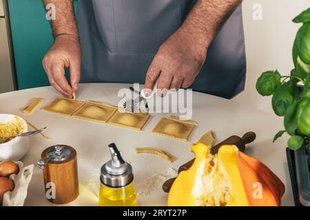 Soggiorno a casa e cucina. Ravioli di ricotta di zucca italiana fatti in casa, processo di stampaggio dei ravioli. Foto Stock