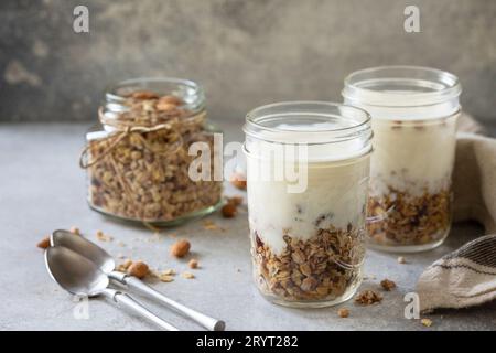 Colazione sana, yogurt parfait. Yogurt con granola di mandorle fatta in casa su sfondo grigio di cemento. Spazio di copia. Foto Stock